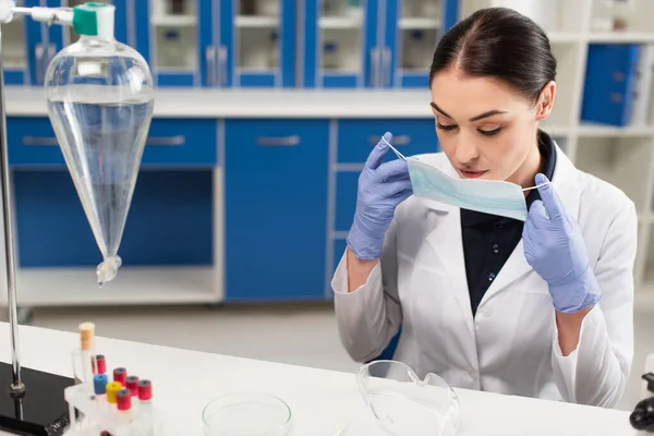 Científico Sosteniendo Máscara Médica Cerca Del Equipo Gafas Laboratorio — Foto de Stock