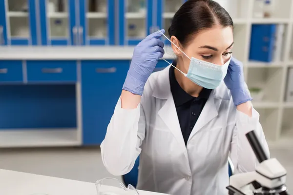 Vědec Nosí Lékařskou Masku Poblíž Rozmazaného Mikroskopu Laboratoři — Stock fotografie