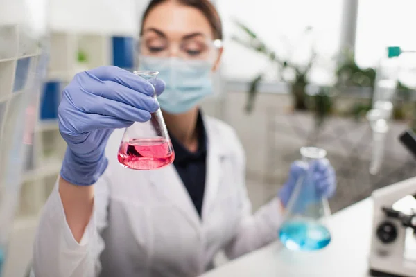 实验室里戴乳胶手套拿着瓶的模糊科学家 — 图库照片
