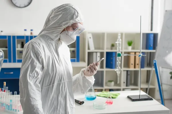 Cientista Terno Protetor Olhando Para Telefone Celular Laboratório — Fotografia de Stock