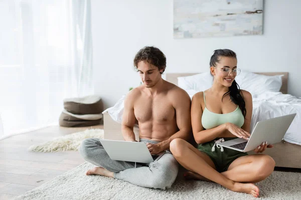 Усміхнена Сексуальна Пара Використовує Ноутбуки Біля Ліжка Вдома — стокове фото