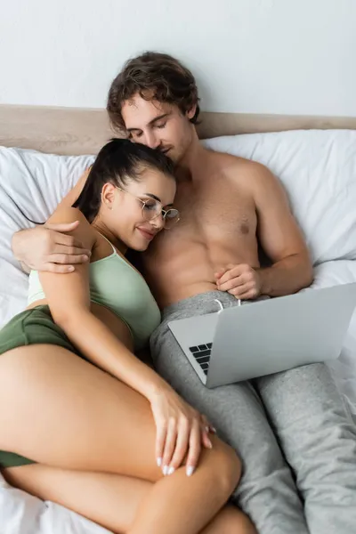 裸男在床上抱着性感女人靠近笔记本电脑 — 图库照片