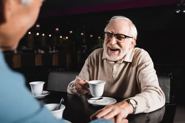 Derűs Idős Férfi Szemüvegben Kezében Egy Csésze Kávéval Miközben Egy — Stock Fotó