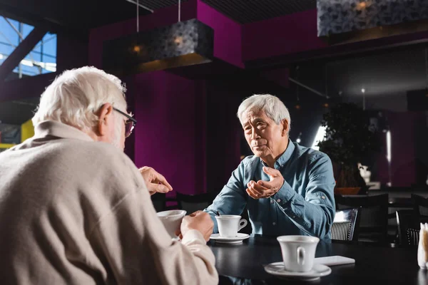 Senior Muži Gestikulace Při Rozhovoru Asijským Přítelem Kavárně Blízkosti Šálky — Stock fotografie