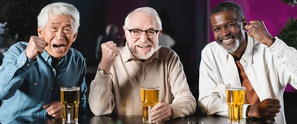 Joyful Senior Multicultural Friends Showing Triumph Gesture While Watching Football — Stock Photo, Image