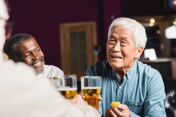 Šťastný Asijský Muž Drží Pivo Hranolky Blízkosti Rozmazané Mnohonárodnostní Přátelé — Stock fotografie