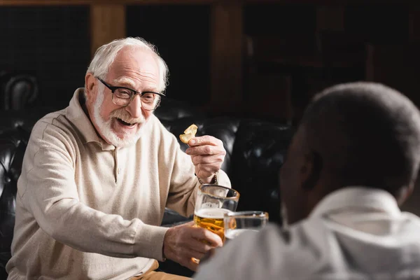 Happy Senior Man Clinking Beer Glasses Blurred African American Friend — Stock Photo, Image
