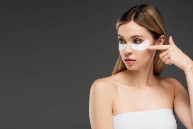 Genç bir kadın gözlerini başka yöne çevirir ve gri renkte izole edilmiş bir yüz bandına bakar.