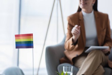 small lgbt flag near cropped psychologist with digital tablet on blurred background clipart