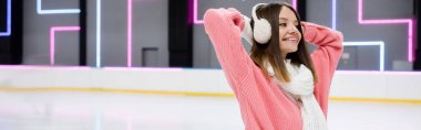 happy young woman in ear muffs and scarf on ice rink, banner clipart