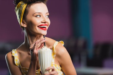 Kafede elinde bir bardak lezzetli milkshake tutan neşeli bir kadın. 