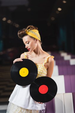 Kırmızı dudaklı genç bir kadın. Retro vinil diskler tutuyor. 