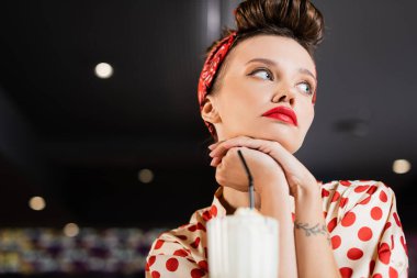 Düşük açılı, üzgün, iğneli, dövmeli, bulanık milkshake 'li kadın. 