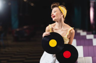 Elinde retro vinil diskler tutan mutlu bir kadın. 
