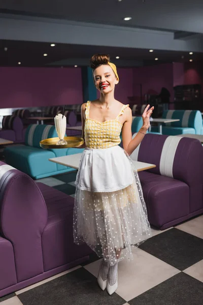 Χαρούμενα Pin Σερβιτόρα Κρατώντας Δίσκο Milkshake Ενώ Gesturing Στην Καφετέρια — Φωτογραφία Αρχείου