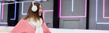 Pembe kazaklı ve beyaz kulaklıklı kadın, afiş.