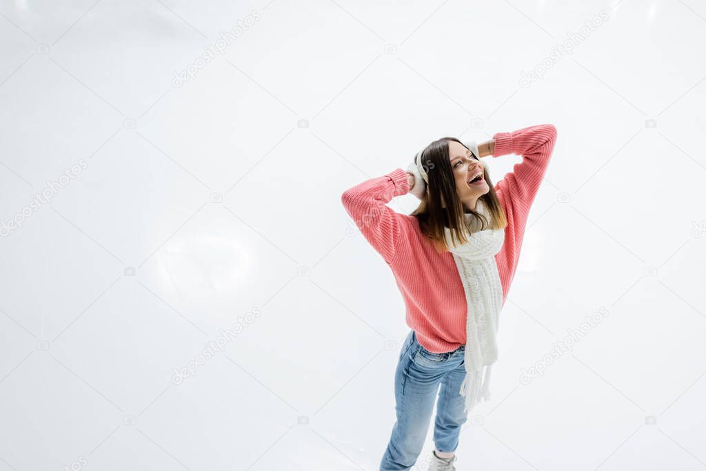 cheerful young woman with tattoo skating and looking up on ice rink