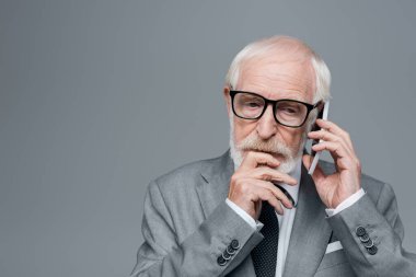 Düşünceli, yaşlı iş adamı. Gri yolda cep telefonuyla konuşuyor.