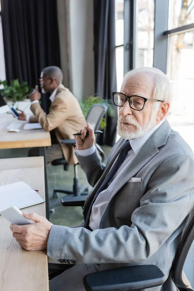 Elderly Businessman Eyeglasses Holding Mobile Phone While African American Colleague — Stock Photo, Image