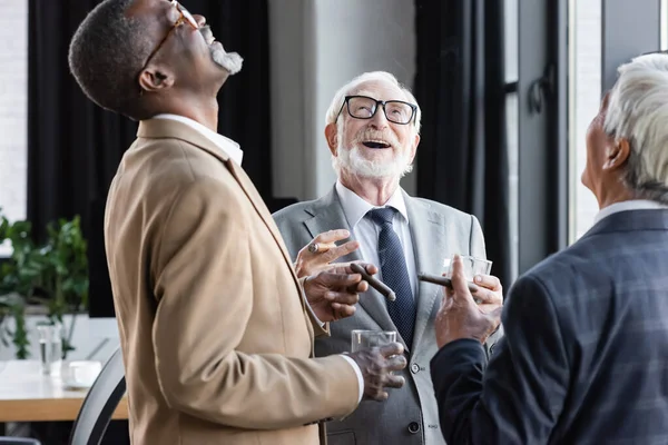 Äldre Multietniska Affärsmän Skrattar Medan Dricker Whisky Och Röker Cigarrer — Stockfoto