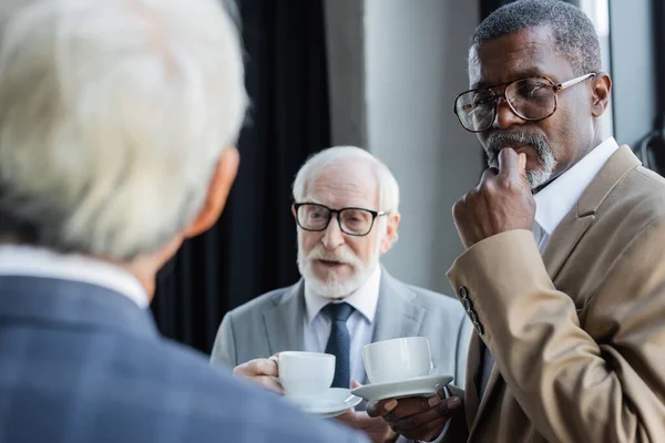 Mayores Hombres Negocios Interracial Con Tazas Café Mirando Borrosa Colega — Foto de Stock