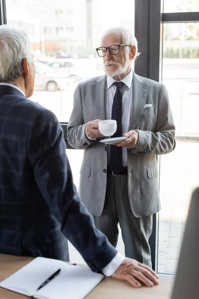 Senior Affärsman Glasögon Som Håller Kopp Kaffe Medan Pratar Med — Stockfoto