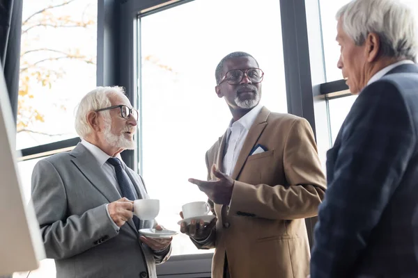 Empresário Afro Americano Apontando Com Mão Enquanto Conversa Com Colegas — Fotografia de Stock