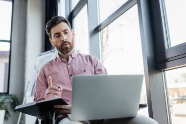 İş adamı bilgisayarında görüntülü sohbet sırasında dizüstü bilgisayarını tutuyor. 