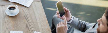 Bulanık iş adamının gazetenin yanındaki akıllı telefonu ve ofisteki kahveyi gösteren yüksek açılı görüntüsü, afiş. 