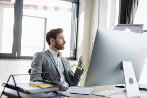 Side view of businessman sitting near computer and notebook in office 