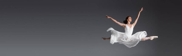 Полная длина изящной женщины в белом платье прыжки изолированы на серый, баннер