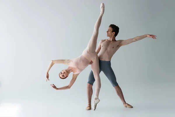 Shirtless Ballet Dancer Supporting Flexible Ballerina Outstretched Hands Isolated Grey — Stock Photo, Image