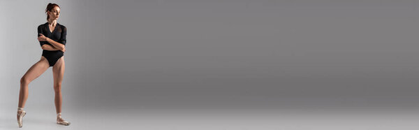 на всю длину рыжеволосая балерина в черном купальнике танцующая на темно-сером, баннер