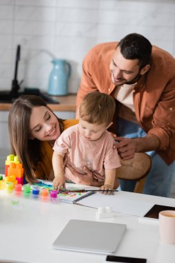 Gülümseyen aile, evdeki yapı taşları ve eskiz defterinin yanında oğluna bakıyor. 
