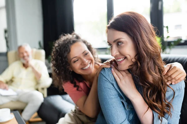 Pareja Lesbiana Multiétnica Sonriendo Cerca Psicóloga Borrosa Sala Consulta — Foto de Stock