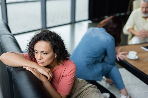 失望したアフリカ系アメリカ人女性がレズビアンのガールフレンドや心理学者の近くのソファに座って — ストック写真