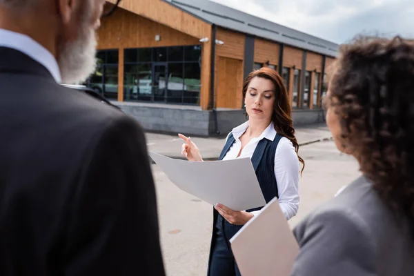 Fastighetsmäklare Peka Byggnad Samtidigt Som Man Tittar Plan Nära Suddig — Stockfoto