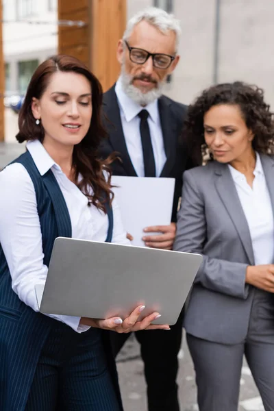 Immobilienmakler Mit Laptop Der Nähe Afrikanischer Amerikanerin Und Verschwommenem Geschäftsmann — Stockfoto