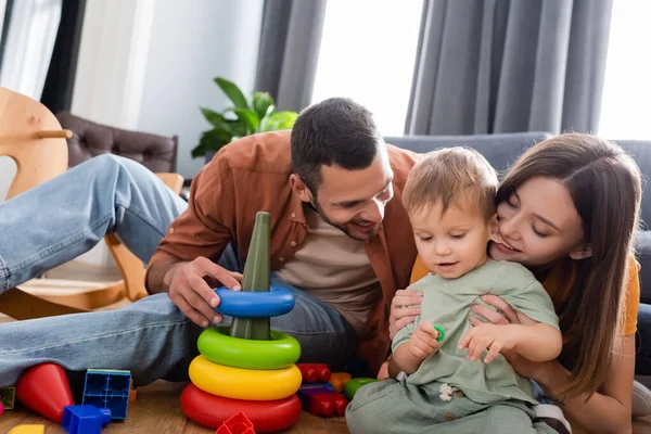 快乐的父母坐在儿子身边 玩具在客厅里 — 图库照片