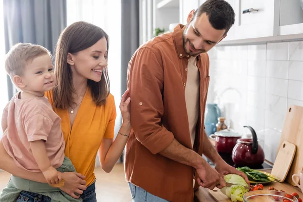 Mulher Sorridente Segurando Criança Perto Marido Cozinhar Cozinha — Fotografia de Stock