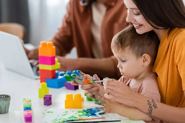 Feliz Mamá Pintura Mano Hijo Cerca Bloques Construcción Marido Utilizando — Foto de Stock