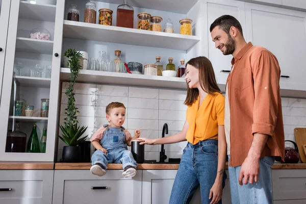 Parents Heureux Regardant Fils Étonné Assis Sur Plan Travail Cuisine — Photo