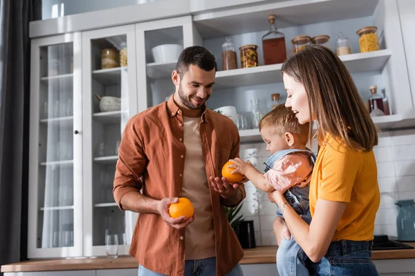 Padre Sosteniendo Naranjas Cerca Esposa Con Hijo Casa — Foto de Stock