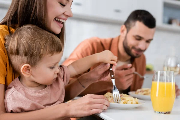 Mujer Feliz Hijo Sosteniendo Tenedor Cerca Pasta Jugo Naranja Cocina — Foto de Stock