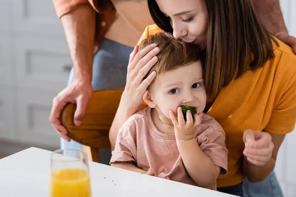 Tânără Femeie Sărutat Fiu Mănâncă Broccoli Bucătărie — Fotografie, imagine de stoc