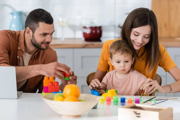 Mujer Sonriente Pintando Con Niño Cerca Marido Portátil Casa — Foto de Stock