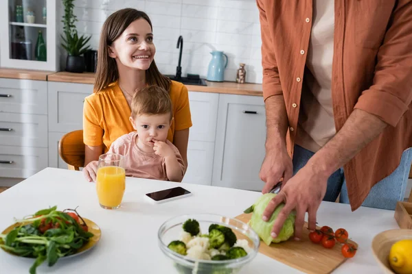 Femeie Veselă Uită Salata Gătit Soțului Lângă Fiu Smartphone Acasă — Fotografie, imagine de stoc