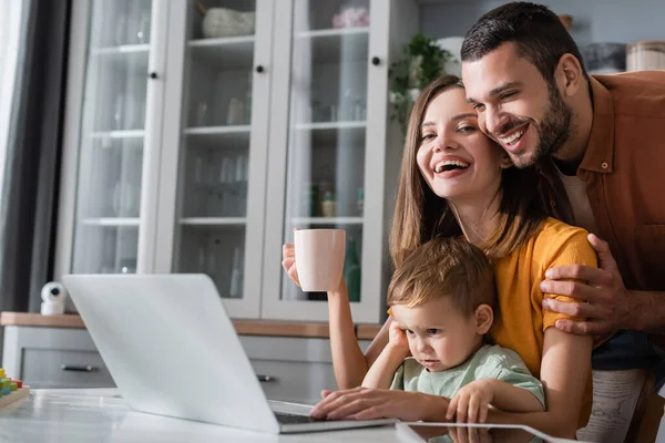 Positive Man Hugging Wife Cup Kid Devices Home — Stock Photo, Image