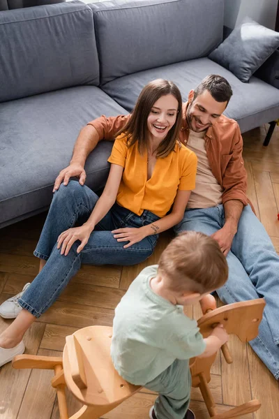 Vista Alto Angolo Genitori Sorridenti Seduti Vicino Figlio Dondolo Casa — Foto Stock