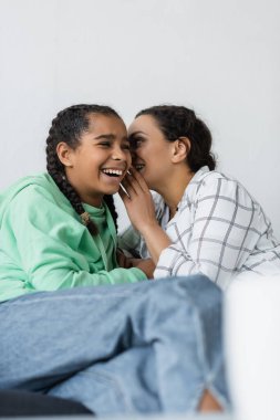 Afro-Amerikan kadın bulanık ön planda neşeli kızına sırrını anlatıyor.